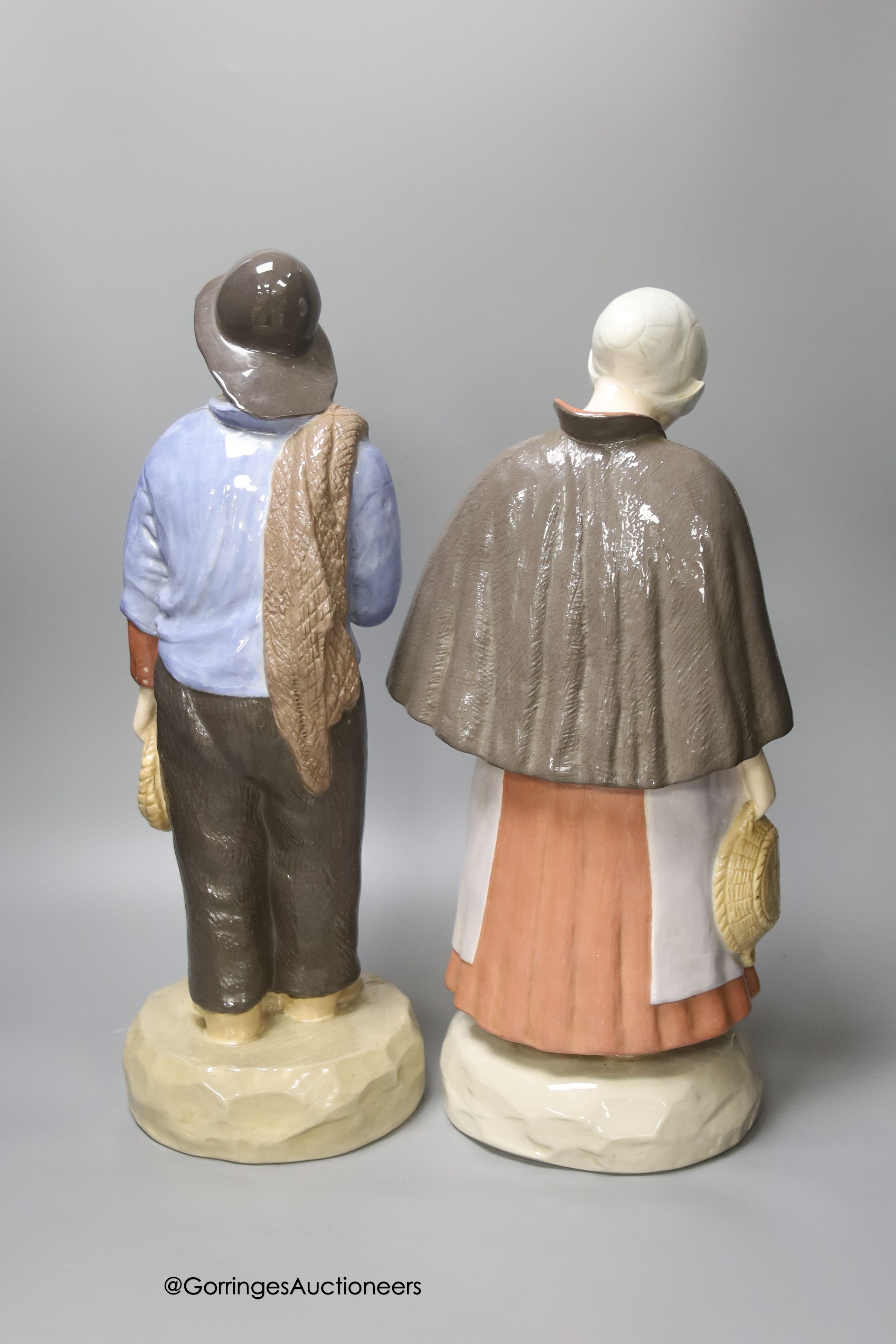 A pair of large Gouda pottery figures of a fisherman and fisherwoman, inscribed 'Scheveningen', 41cm